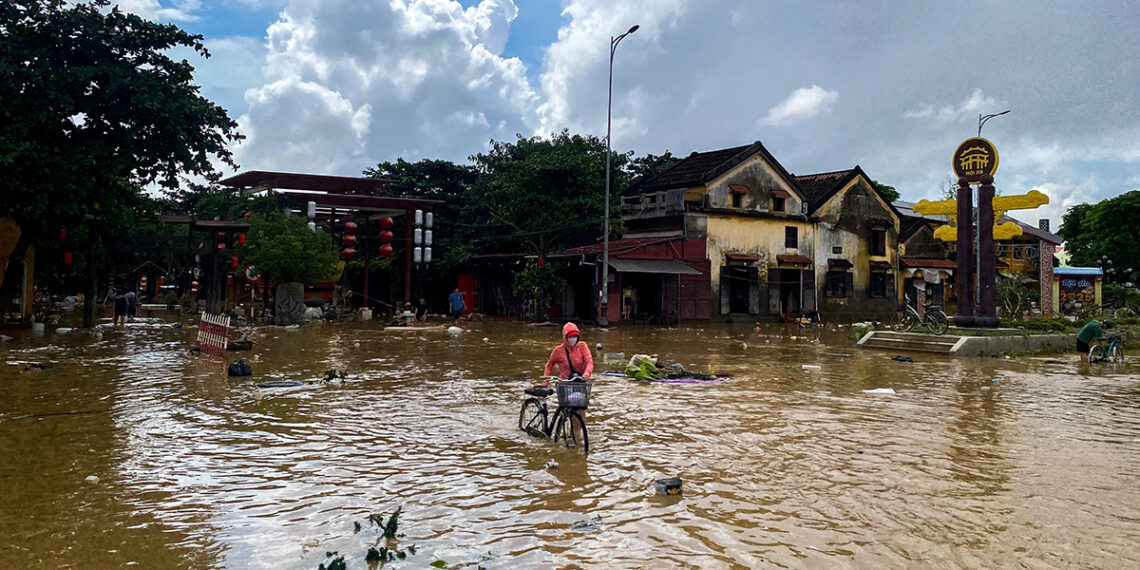 A woman with a cycle wades through a flooded street in Hoi An, following deadly floods in central Vietnam, October 31, 2025. REUTERS/Thinh Nguyen